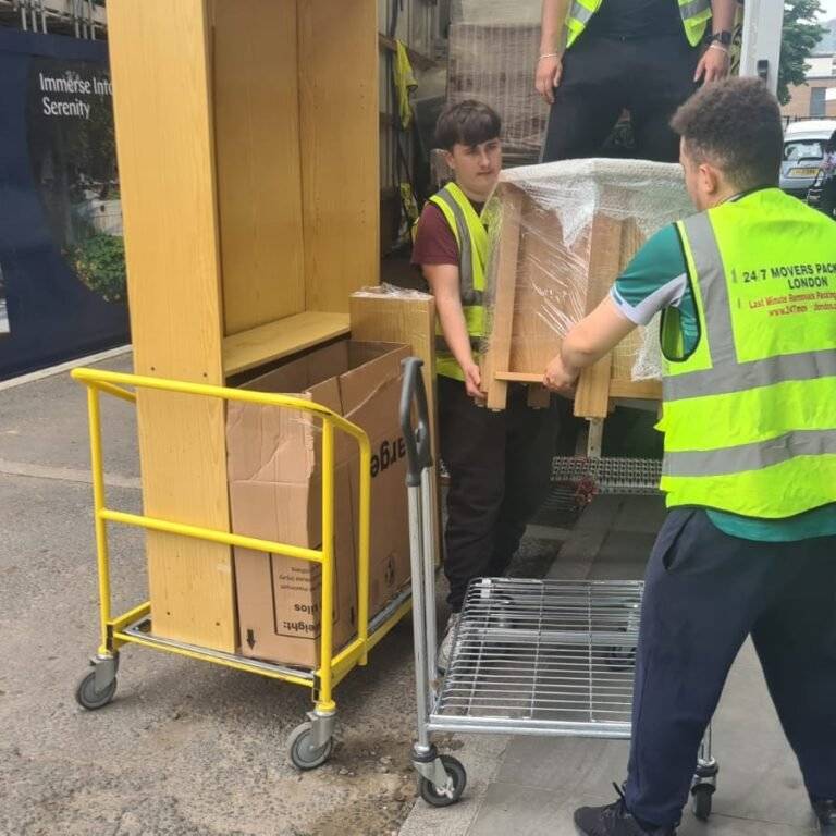 two man are loading packed items into the truck\van