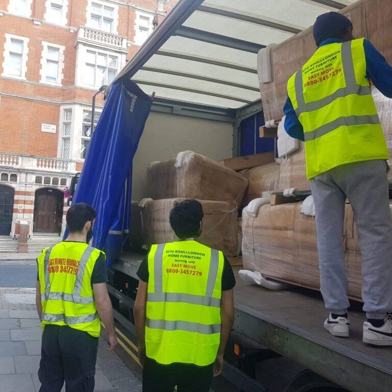 Two man are standing near the truck and other is on the truck