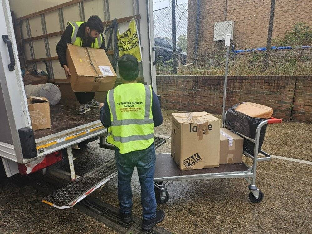 Two man are unloadingMaking Your Moves Memorable with our Top Notch Services the boxes from the truck in the trolley